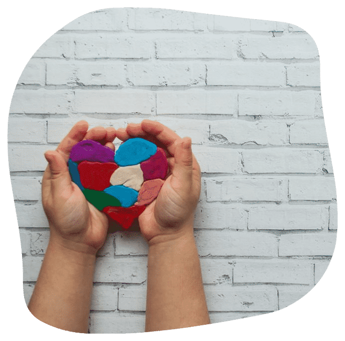 Child's Hands Holding A Multicolored Heart On White Background