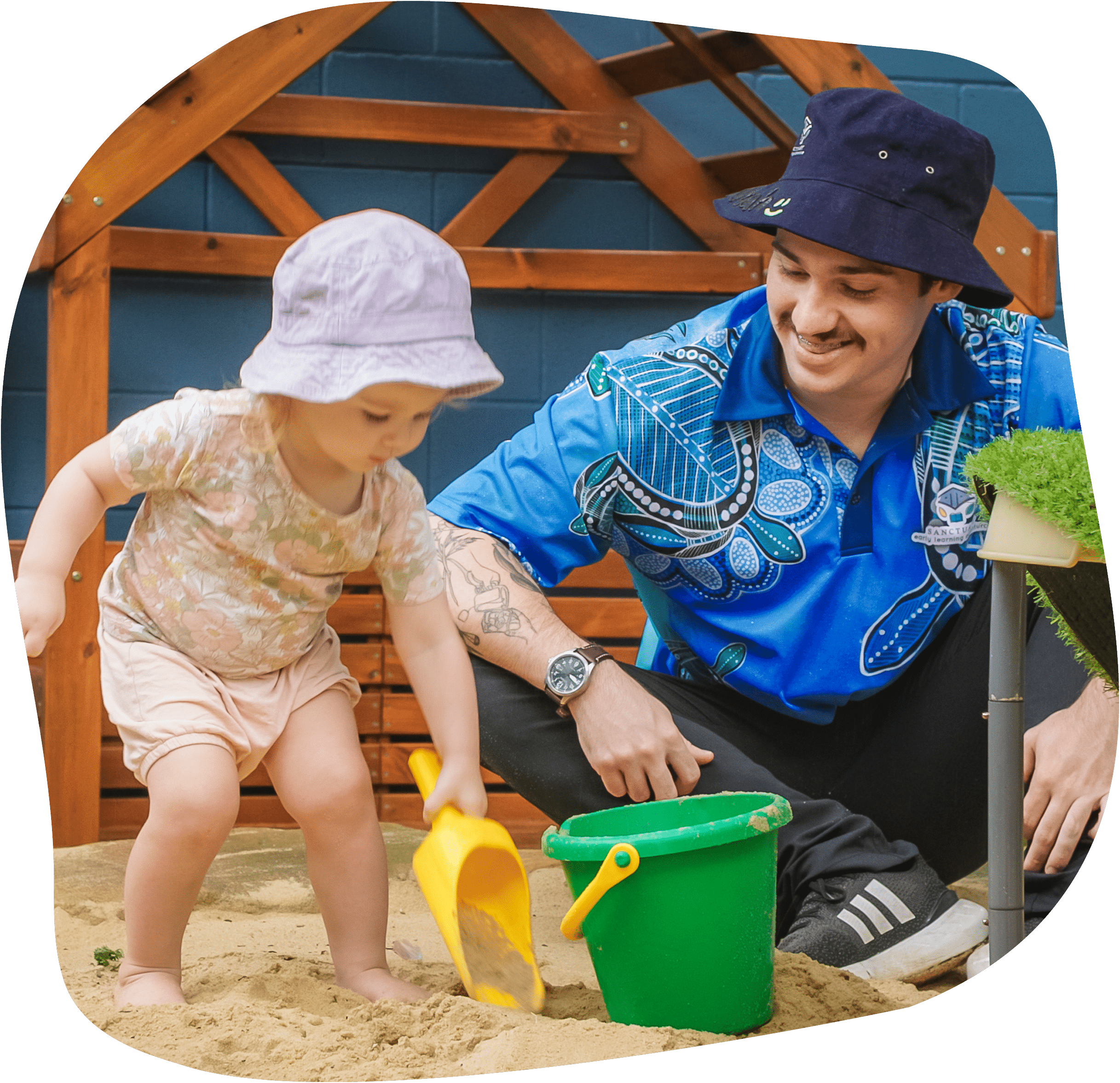 Early learning staff member playing in sand with young child