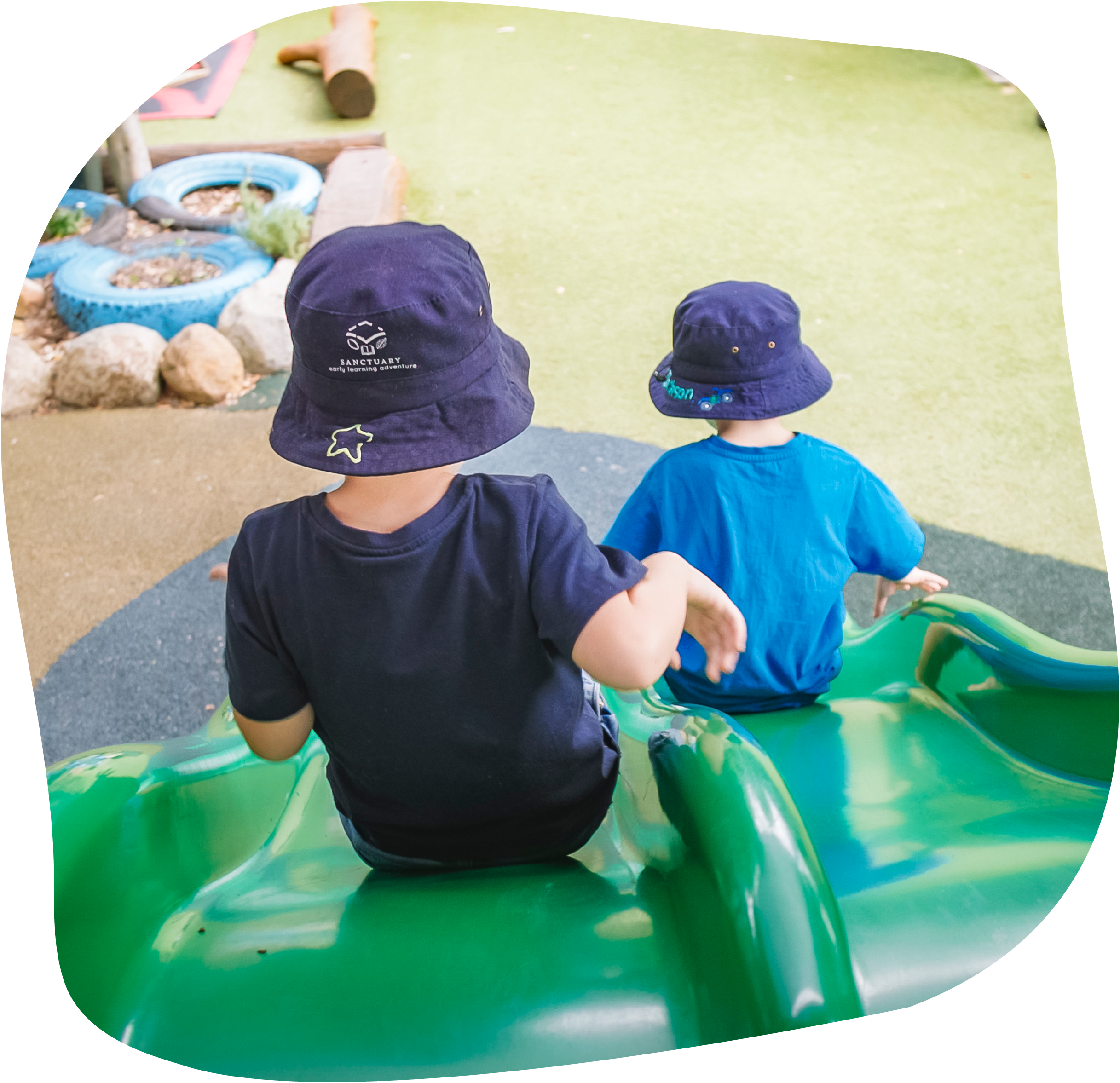 Two kids sliding down green play slide