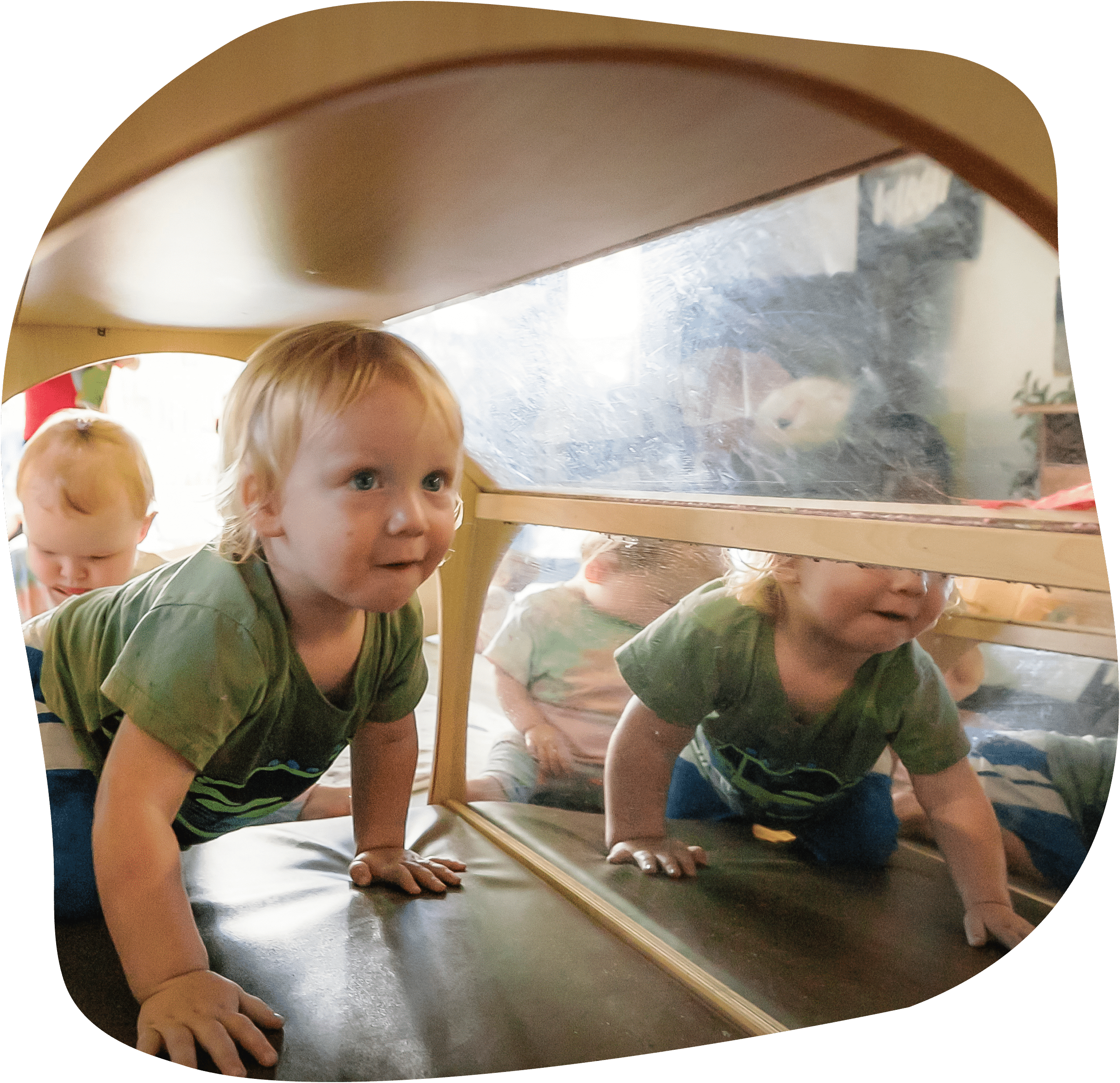 Two babies crawling through tunnel in early learning centre
