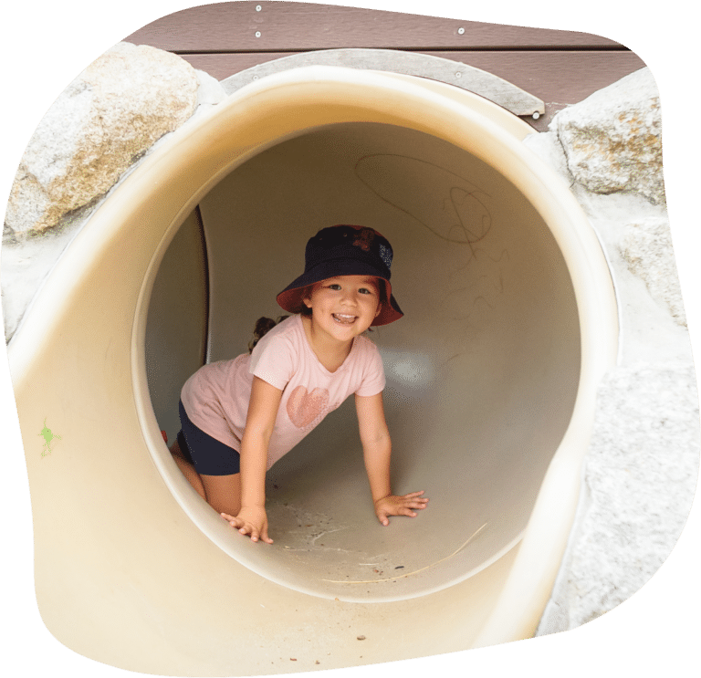 Little girl playing in tunnel after sliding down