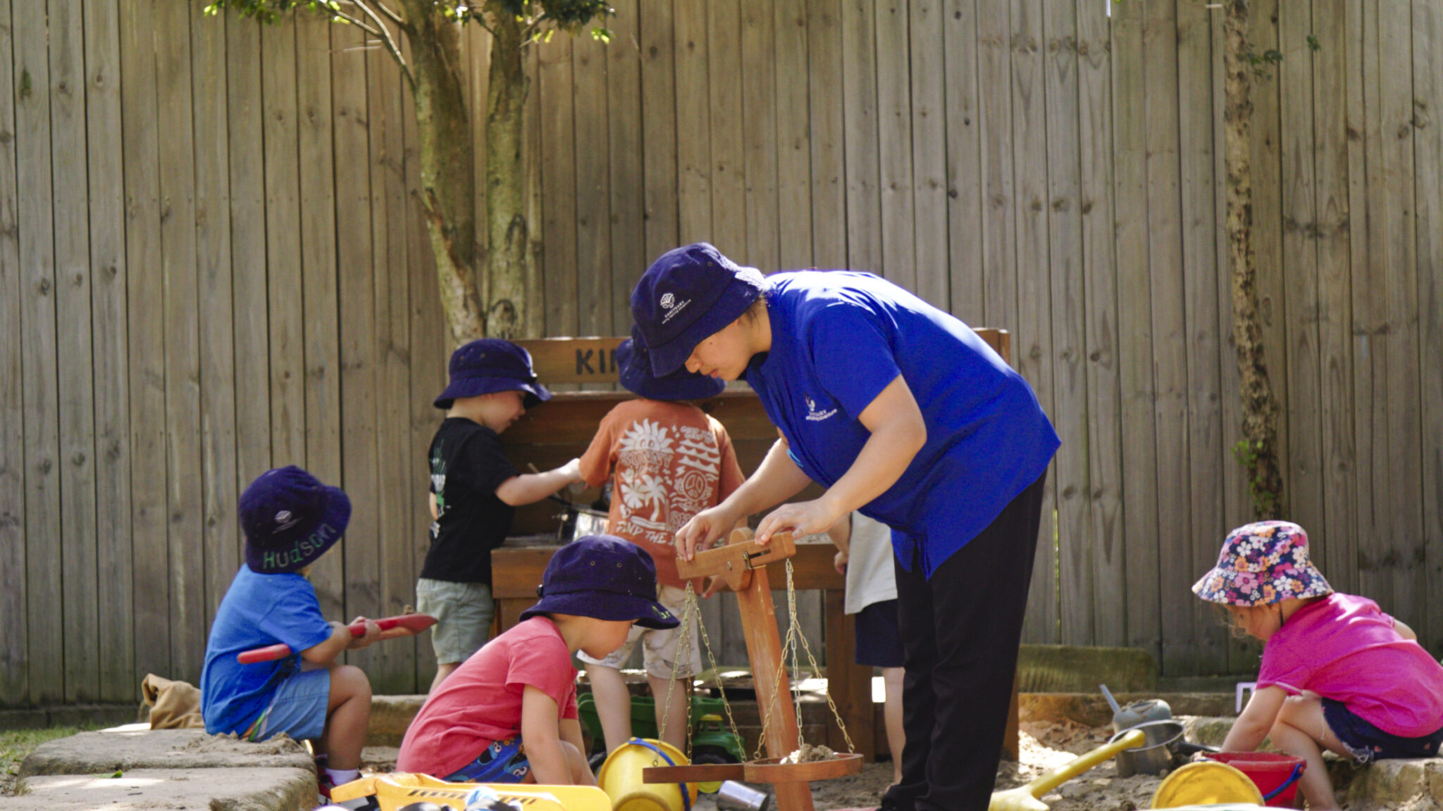 Educator working with a child to balance some scales in the sandpit