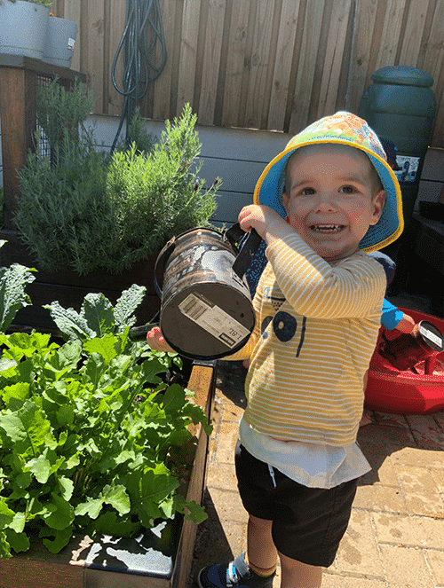 Happy Little Boy Watering Plants From The Garden — Early Learning Centre Ashmore,QLD
