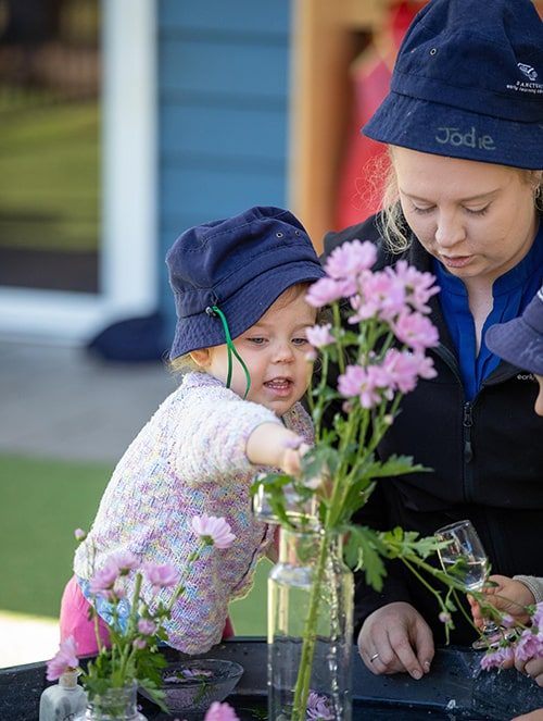 Kid and adult managing flowers — Early Learning Centre in Buderim, QLD