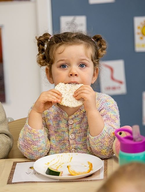 Little girl eating bread — Early Learning Centre in Buderim, QLD