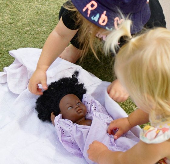 Two Young Girls Playing with A Doll on The Grass — Early Learning Centre Maudsland,QLD