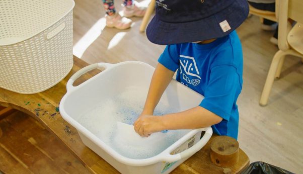 Young Boy Washing a White Container — Early Learning Centre Maudsland,QLD