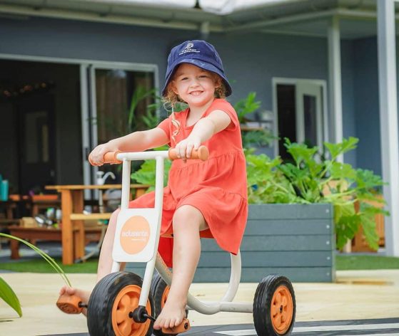 Young Girl Happily Rides a Tricycle in Front of A House — Early Learning Centre Maudsland,QLD